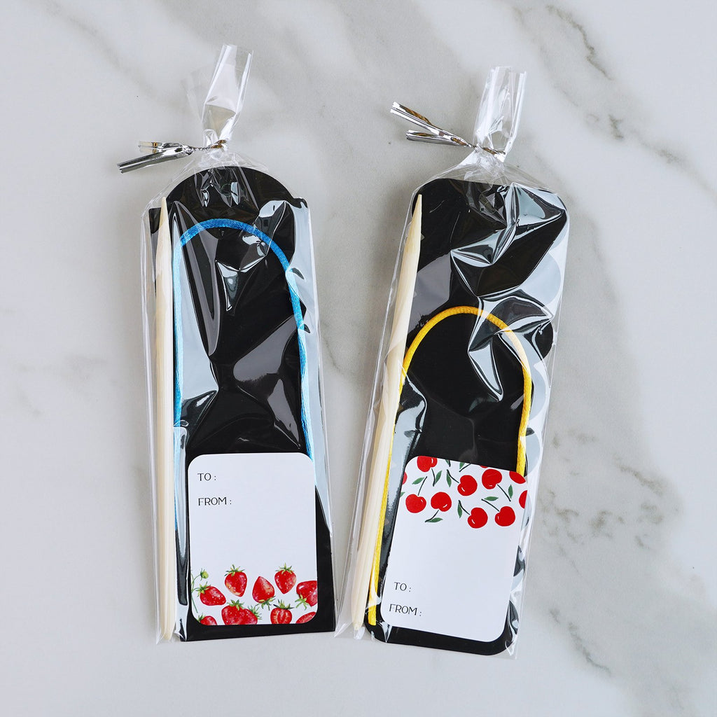 Two scratch art bookmark craft kits, each with a black bookmark, wooden stylus, and colorful cord, on a marble surface.