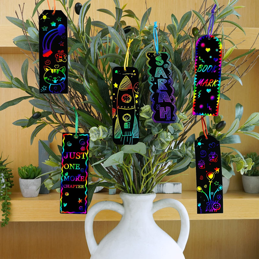 Rainbow scratch art bookmarks with various designs and sayings hanging on a plant branch.