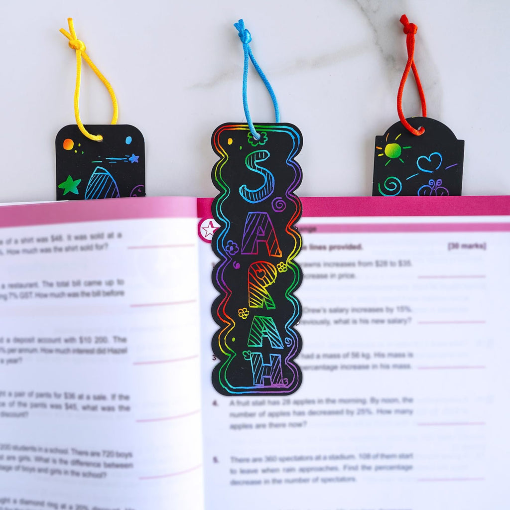 Rainbow scratch art bookmarks with colorful designs and cords peeking out of an open book.
