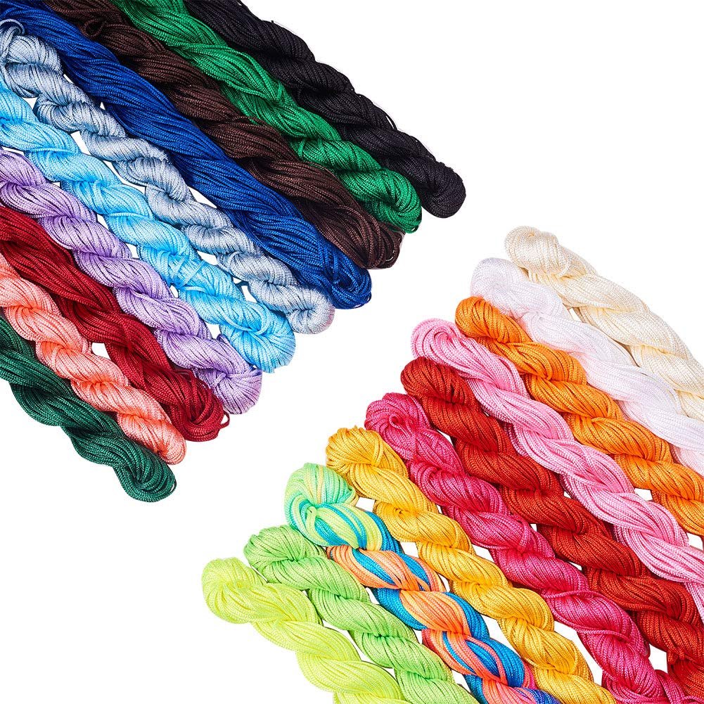 Assortment of 20 spools of colorful nylon knotting cord on a white background, arranged in two diagonal rows.