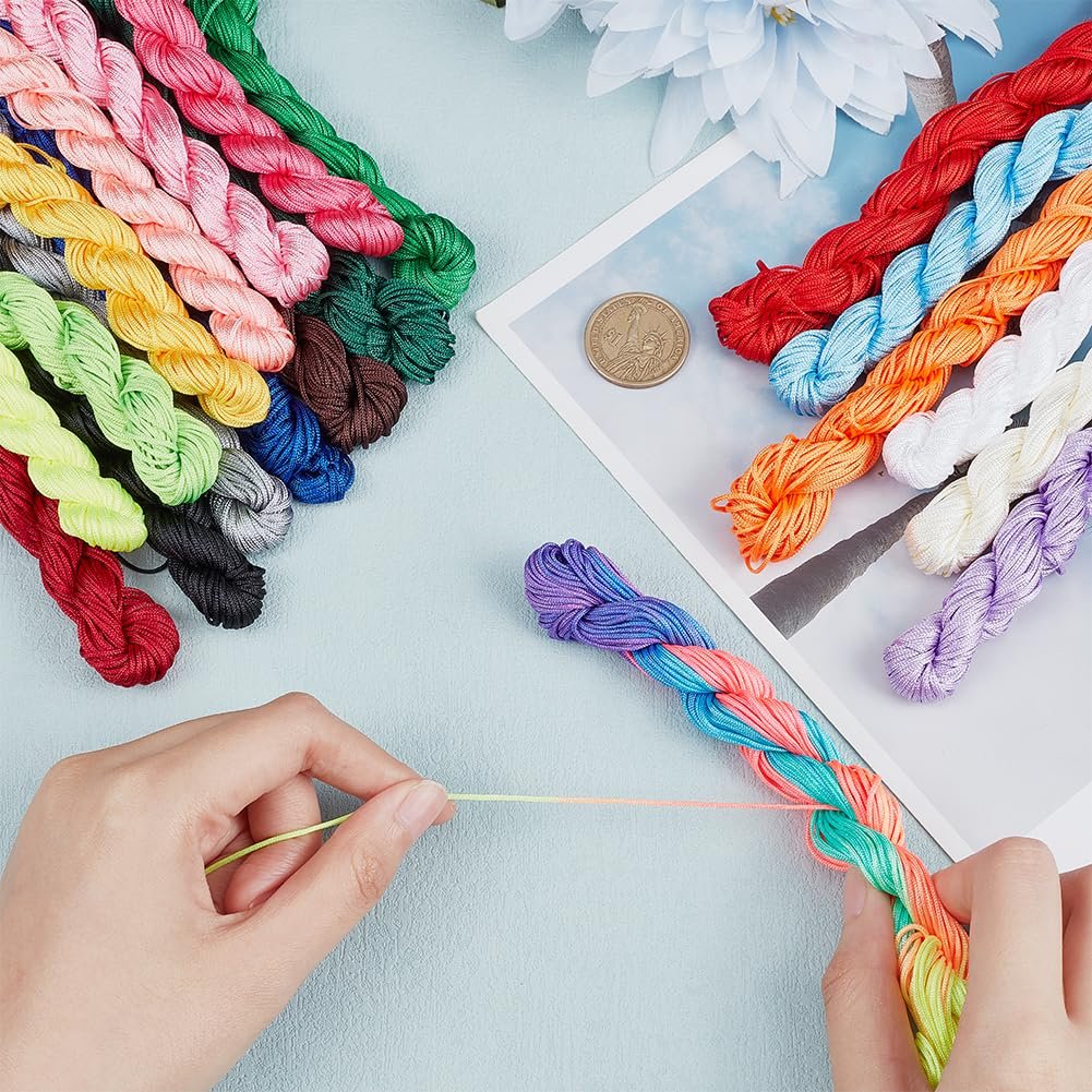 Hands braiding colorful nylon cord for crafts, with spools of cord arranged on a light blue surface.
