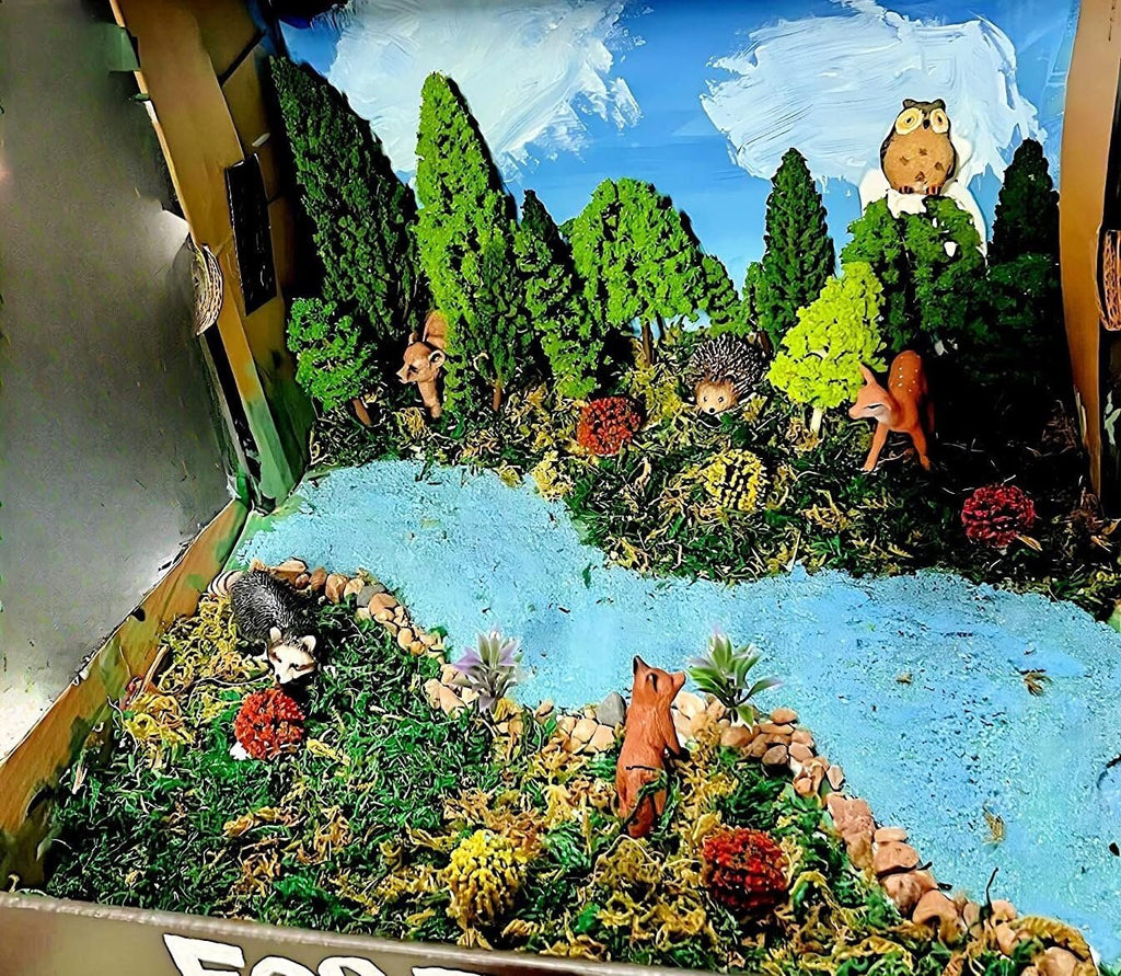 Diorama scene with miniature forest animals, trees, bushes, and a river, set inside a box.