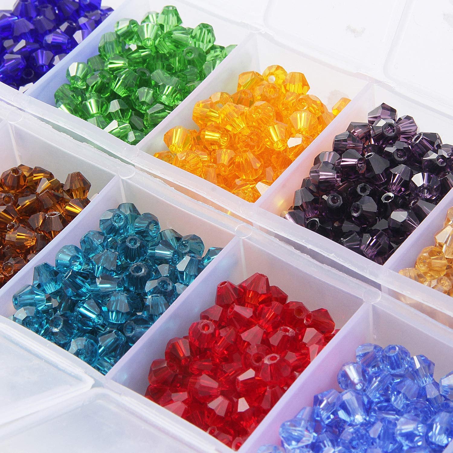 Assorted faceted bicone crystal glass beads in a clear organizer box, showing multiple colors like blue, green, yellow, purple, brown, teal, red, and light blue.