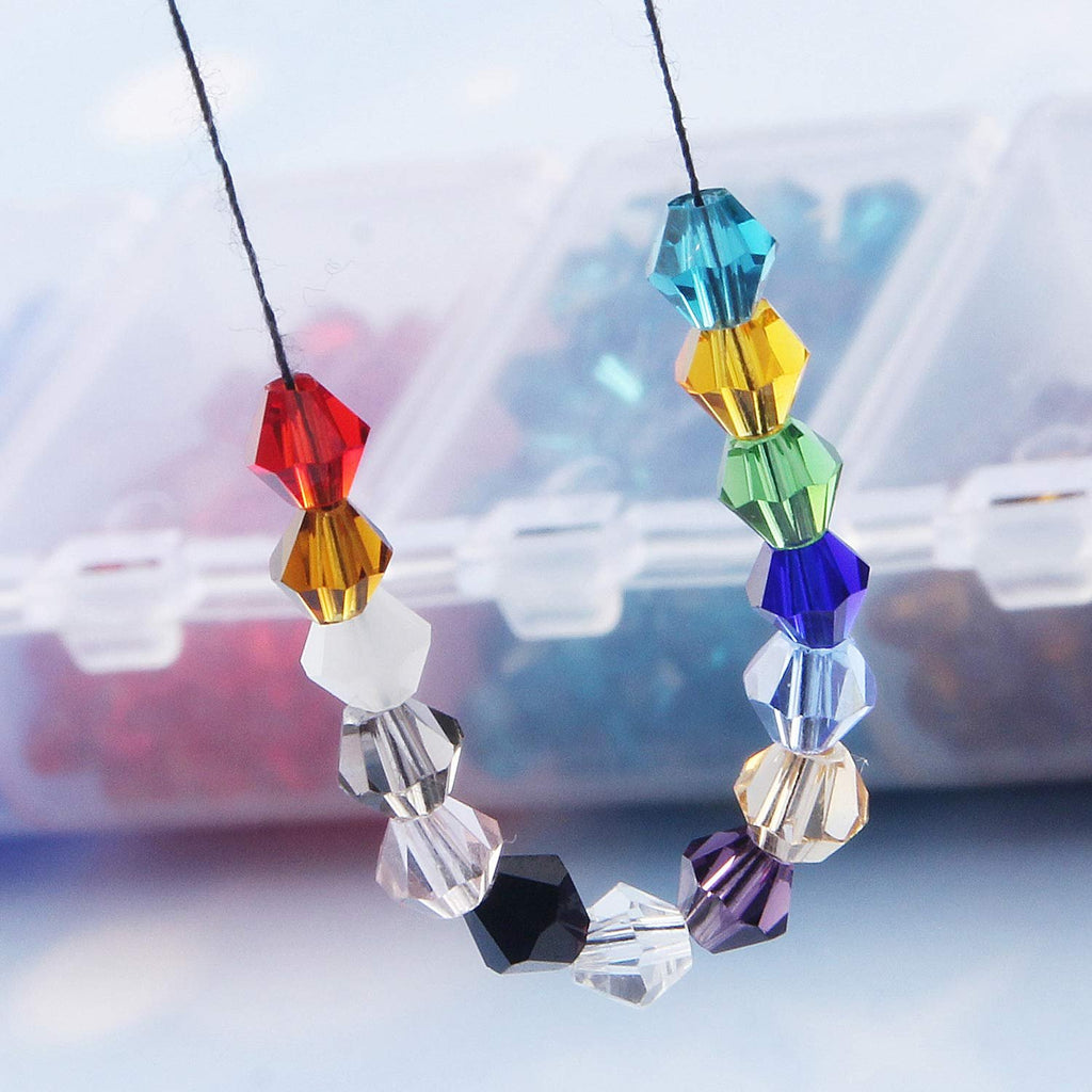 Assorted faceted bicone crystal glass beads strung on black thread, showing a rainbow of colors against a blurred background of a bead organizer.