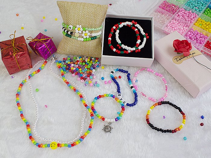 Jewelry making kit with assorted colorful seed beads, finished bracelets, necklaces, and gift boxes.