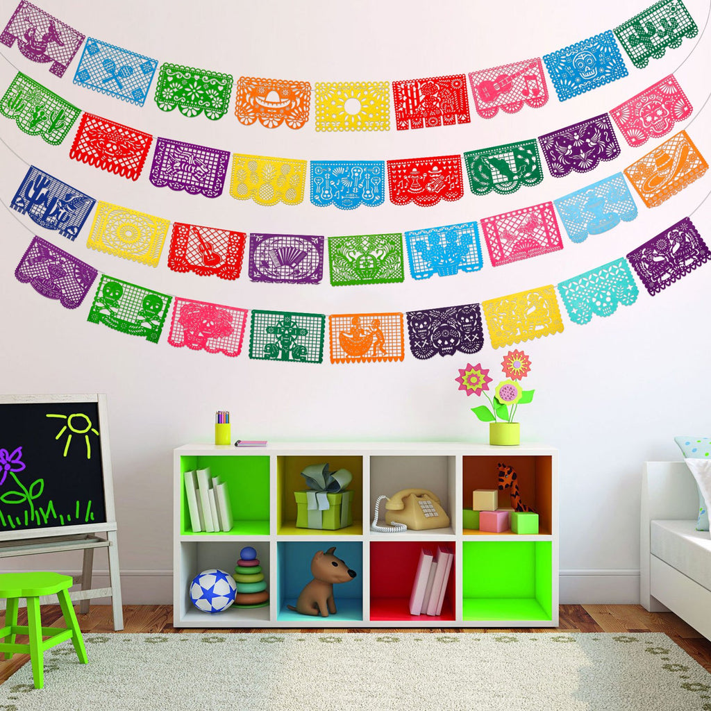 Colorful Papel Picado banners hanging on a white wall above a shelf with toys and books.