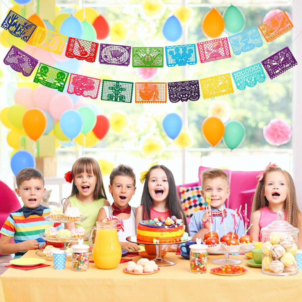 Children at a party table with colorful Mexican Papel Picado banners hanging above