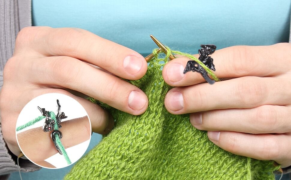 Crocheting with dragon-shaped yarn guide rings on fingers and green yarn