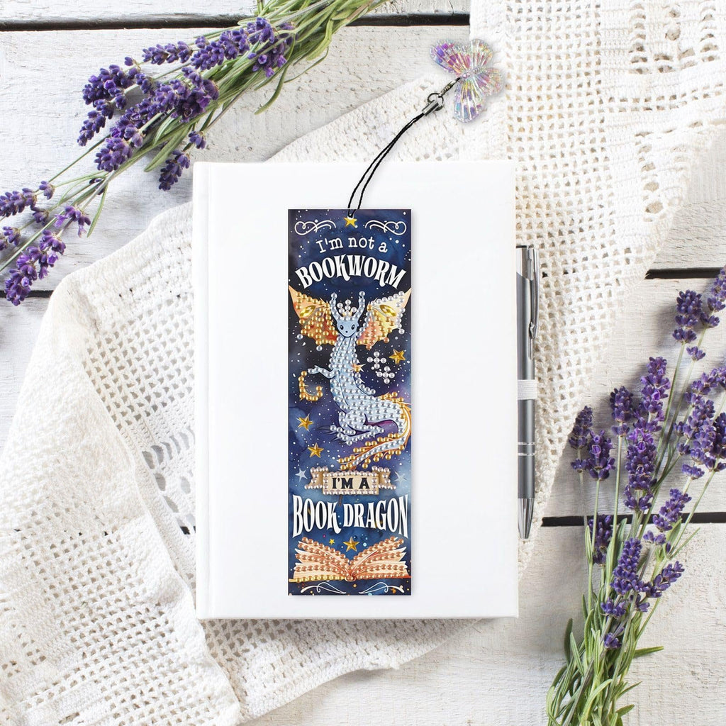 Diamond art bookmark kit with dragon design and rhinestone tassel on a white book with lavender sprigs