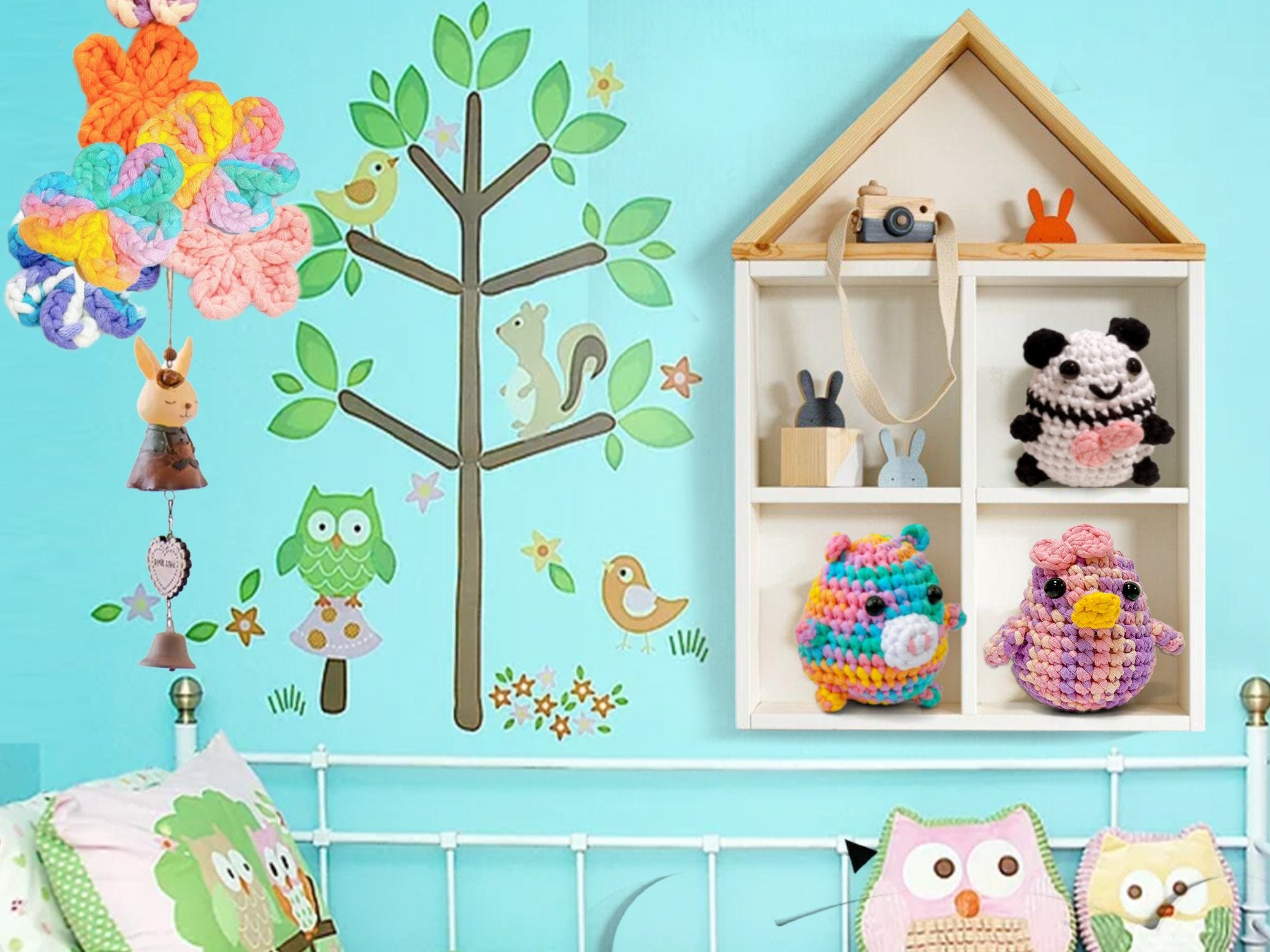 Crocheted stuffed animals and yarn flowers hanging near a wall decal of a tree with animals and a shelf with more stuffed animals.