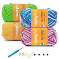 Four balls of yarn in green, yellow, blue/white stripe, and pink/white stripe, with crochet hook and accessories.