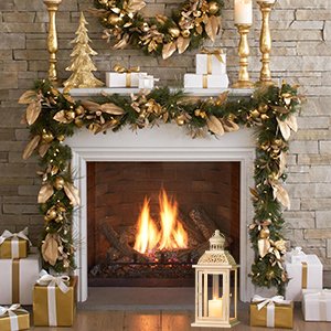 Christmas fireplace decorated with garland, ornaments, candles, gifts, and a white metal lantern with a candle inside.