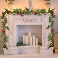 Christmas garland with warm white LEDs, pine needles, red berries draped over a white fireplace mantel with decorative stars and candles.