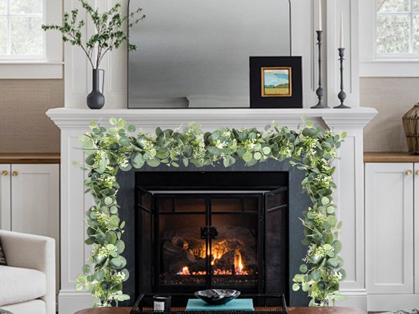 Artificial eucalyptus garland with white blooms draped over a fireplace mantel