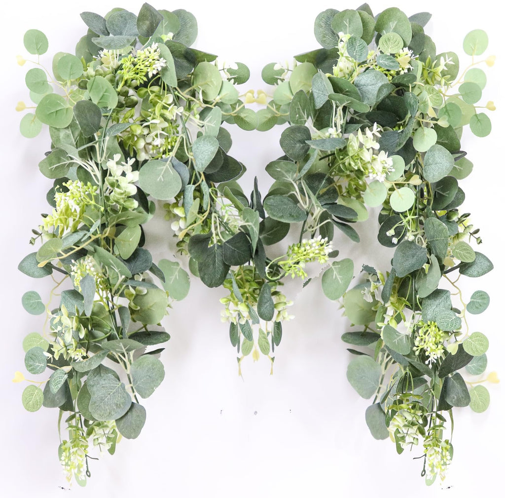 Artificial eucalyptus garland with white blooms draped against a white background.