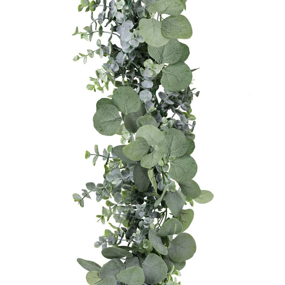 Faux eucalyptus garland with grey-green silk leaves and plastic vine on a white background, close-up view.