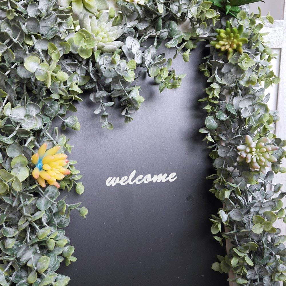 Faux eucalyptus garland with succulents draped over a dark surface with the word 'welcome' in white script.
