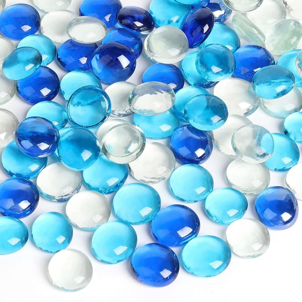 Flat blue and clear glass marbles scattered on a white surface, close-up view.