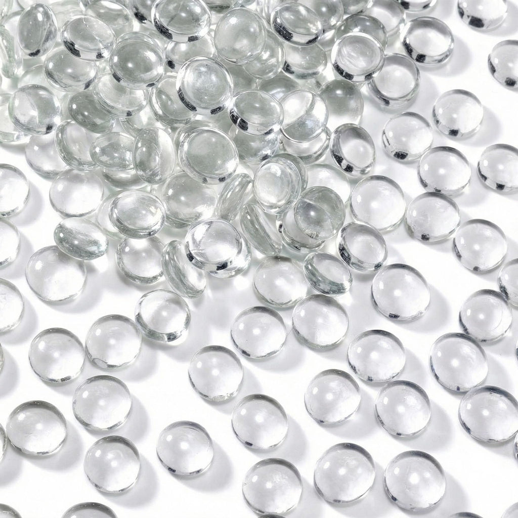 Pile of clear, flat-backed glass marbles on a white surface, showing their rounded tops and flat bottoms.