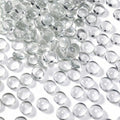 Pile of clear, flat-backed glass marbles on a white surface, showing their rounded tops and flat bottoms.
