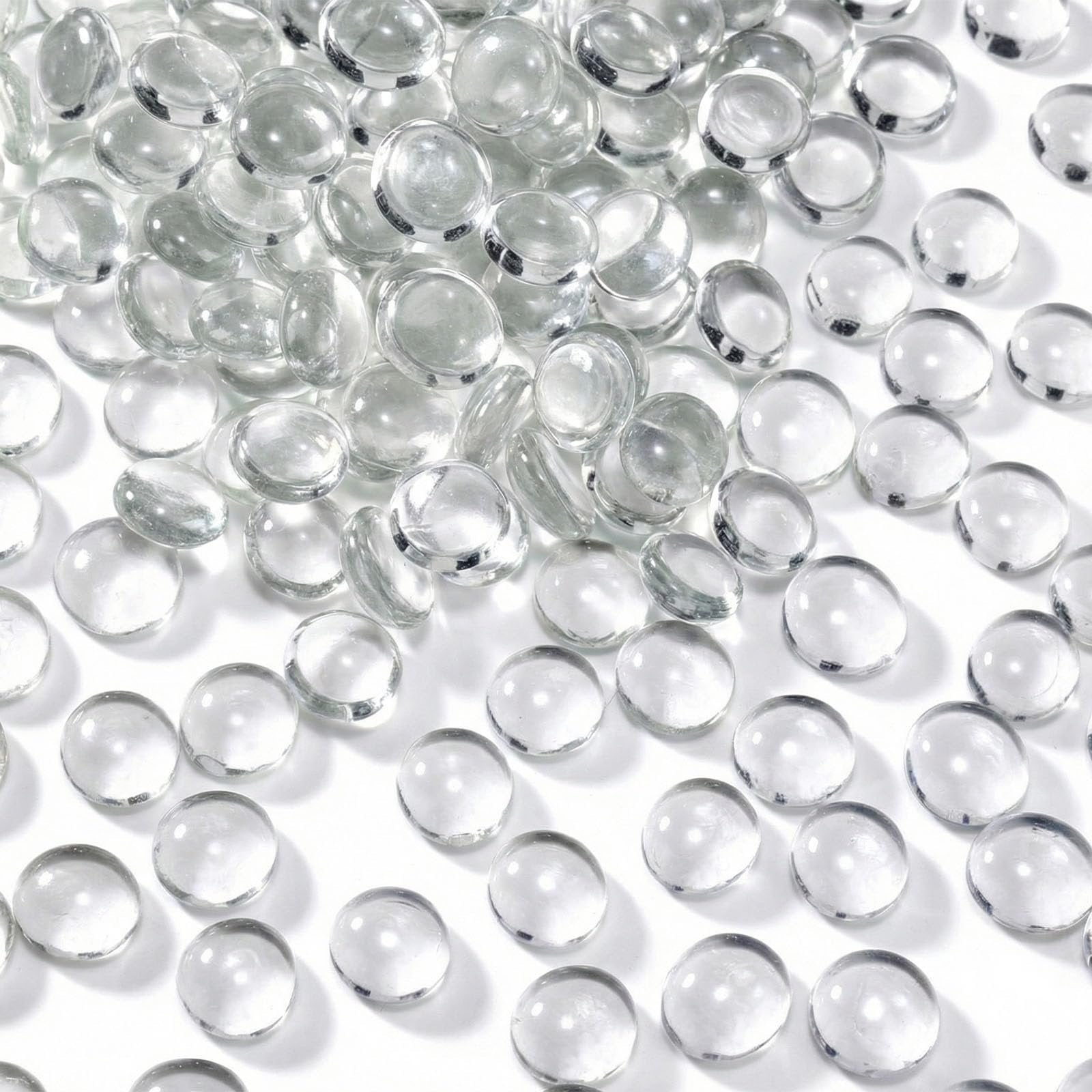 Pile of clear, flat-backed glass marbles on a white surface, showing their rounded tops and flat bottoms.