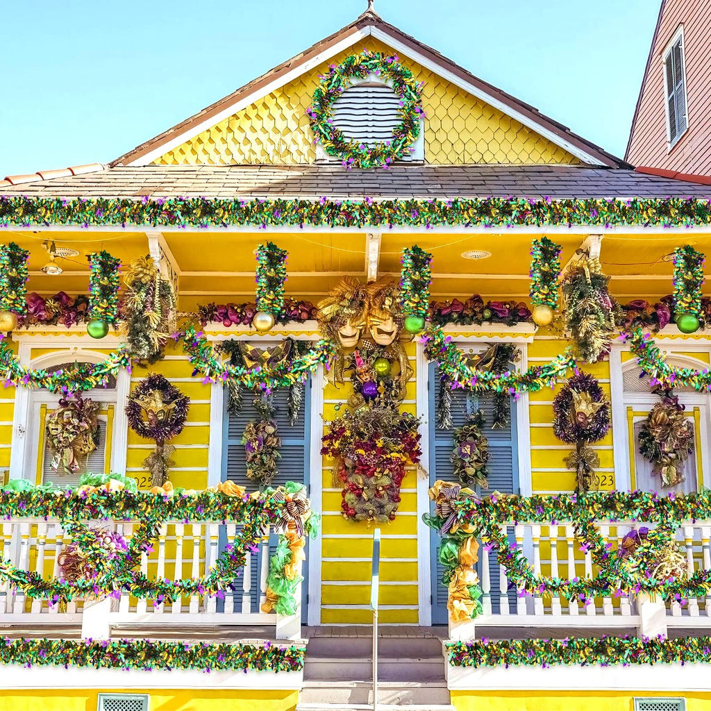 Yellow house decorated for Mardi Gras with purple, green, and gold tinsel garlands and wreaths.