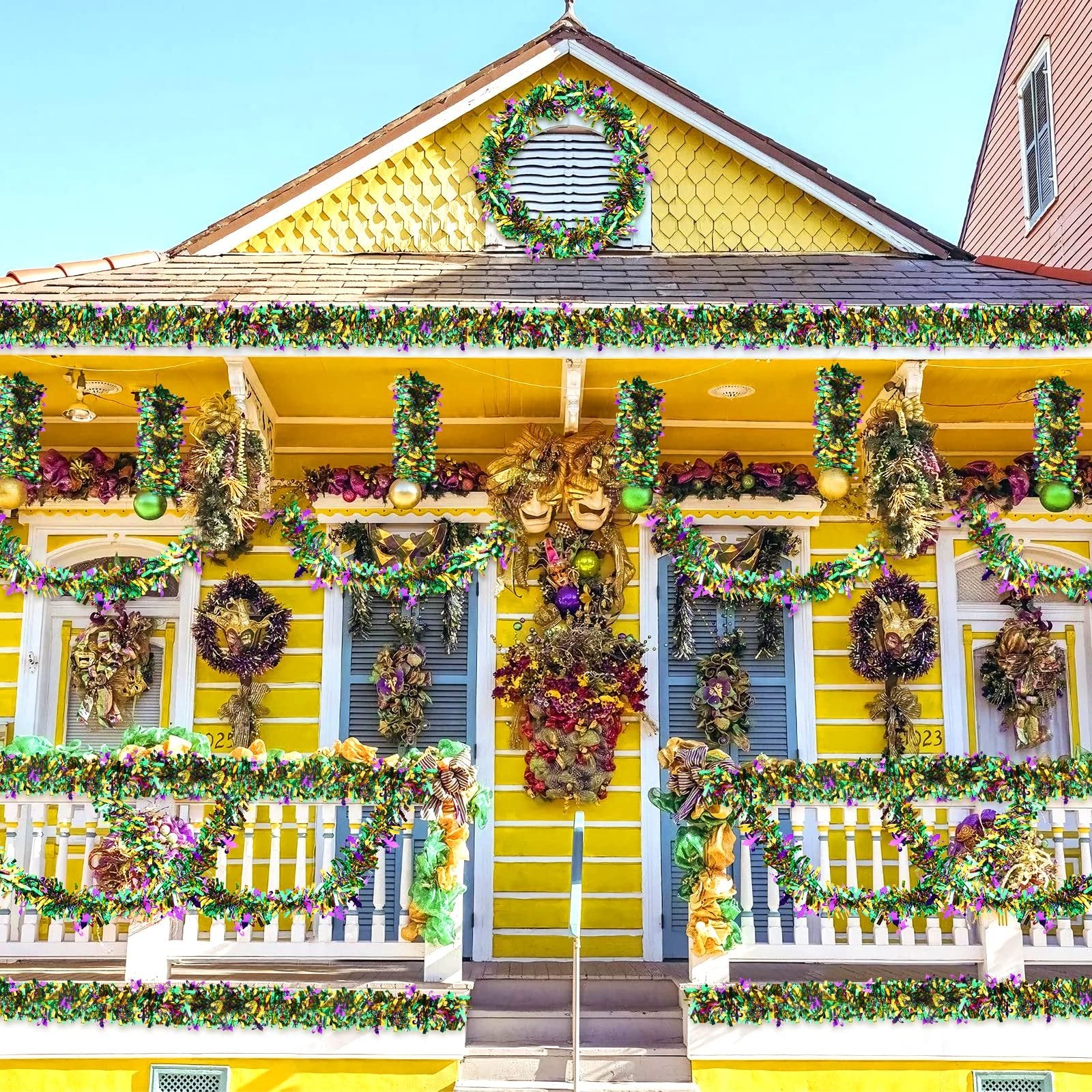 Yellow house decorated for Mardi Gras with purple, green, and gold tinsel garlands and wreaths.