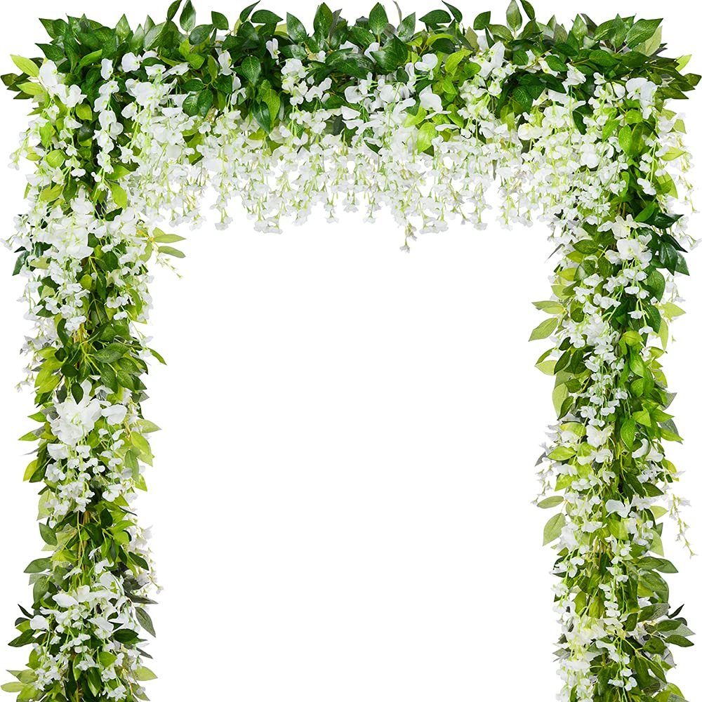Archway formed by artificial white wisteria garlands with green leaves, isolated on white background.