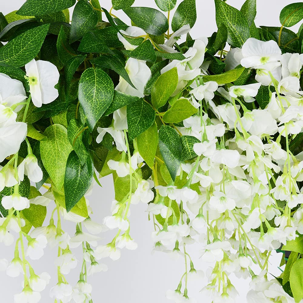 Close-up of white artificial wisteria garland with green leaves against a white background.