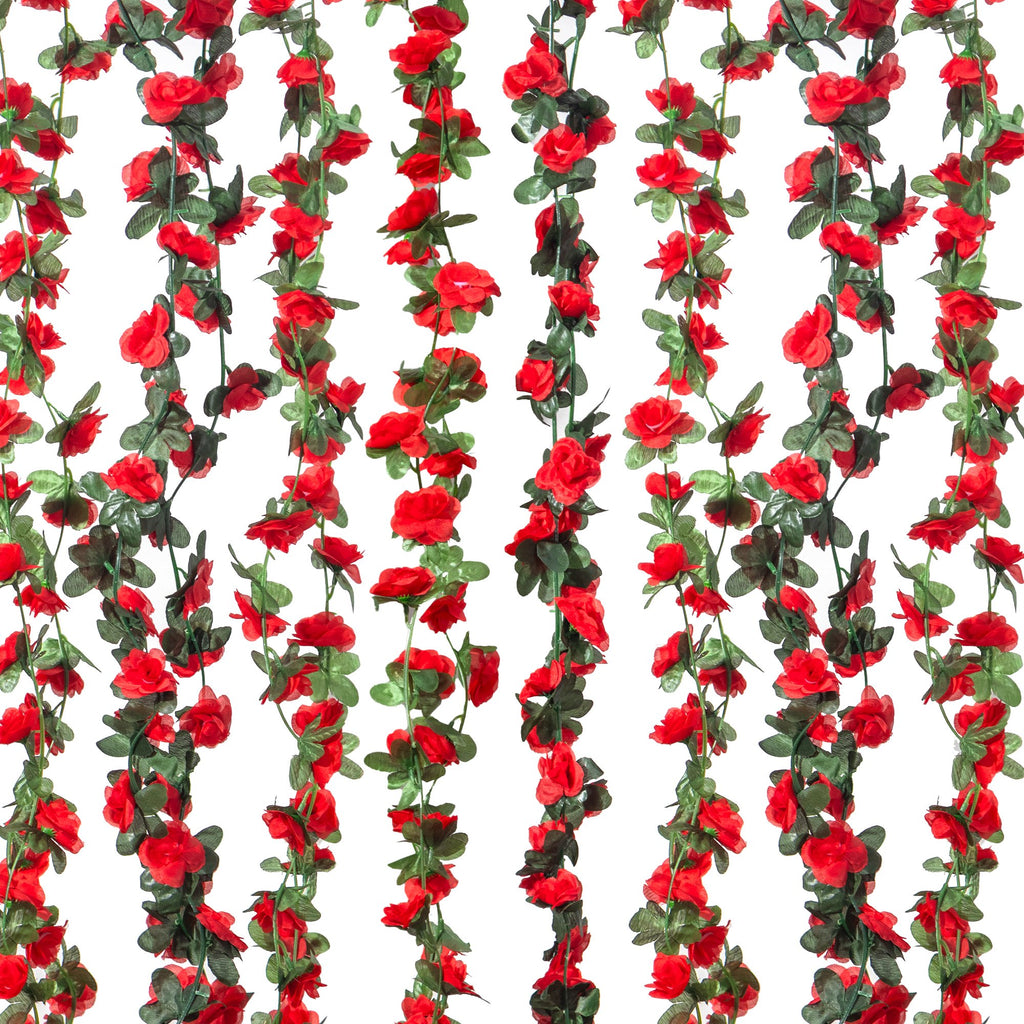 Multiple strands of artificial red rose garlands with green leaves against a white background.