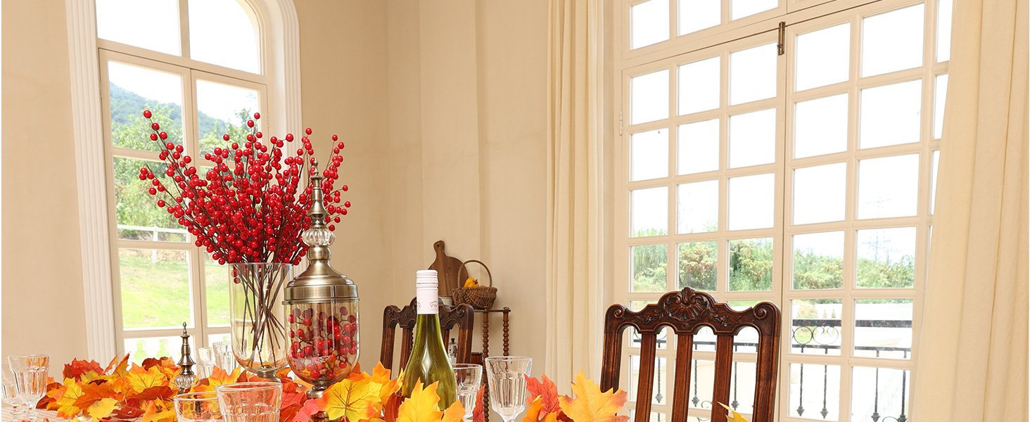 Table setting with artificial maple leaves, red berry branches in a vase, and a bottle of white wine.