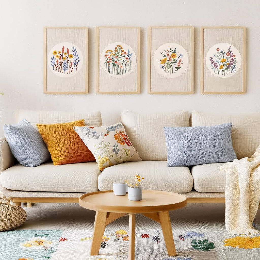 Four framed floral embroidery art pieces hanging above a sofa with decorative pillows and a coffee table.