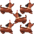 Five brown dachshund shaped foil balloons wearing party hats, arranged in a scattered pattern on a white background.