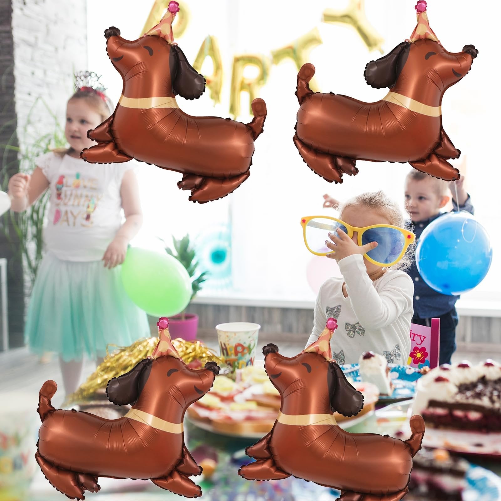 Four dachshund-shaped foil balloons with birthday hats float above a birthday party scene with children.