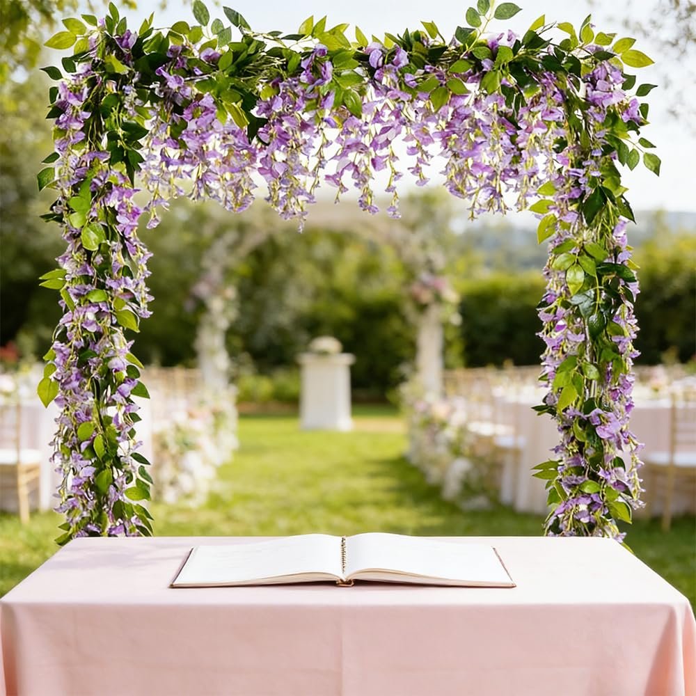 Purple wisteria garland draped over an archway at an outdoor wedding ceremony with a table and open book in the foreground.