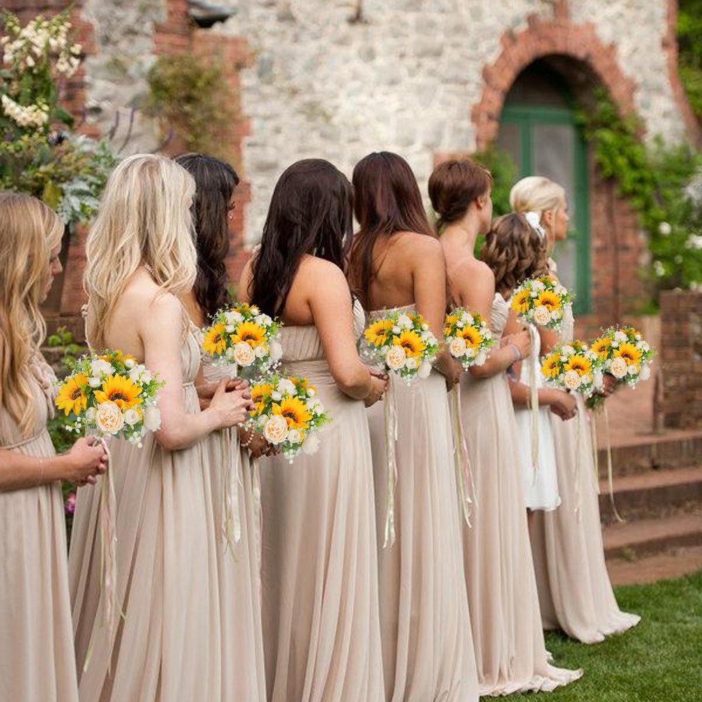 Bridesmaids in champagne dresses holding bouquets of sunflowers and champagne roses outdoors.