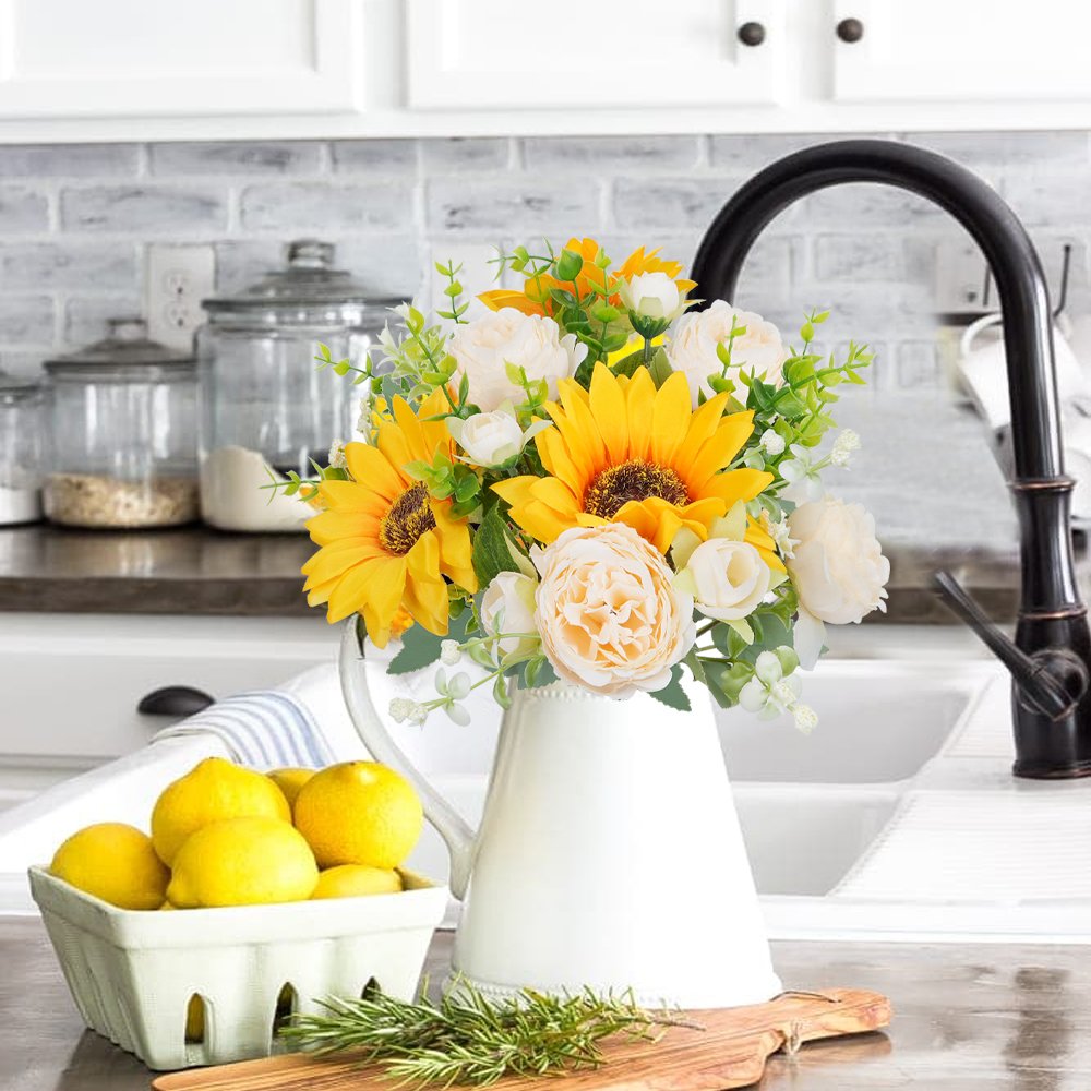 Silk sunflower and peony bouquet in a white pitcher on a kitchen counter with lemons and rosemary
