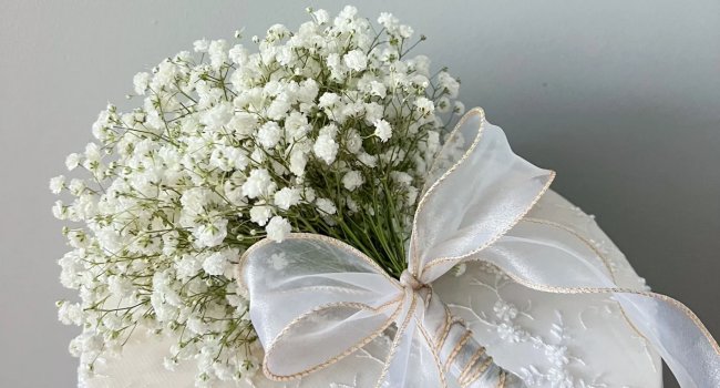 Close-up of a white artificial baby's breath bouquet tied with a sheer ribbon and gold trim.