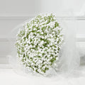 Bouquet of artificial white babys breath flowers wrapped in sheer white tulle, set against a white background with lace detail.