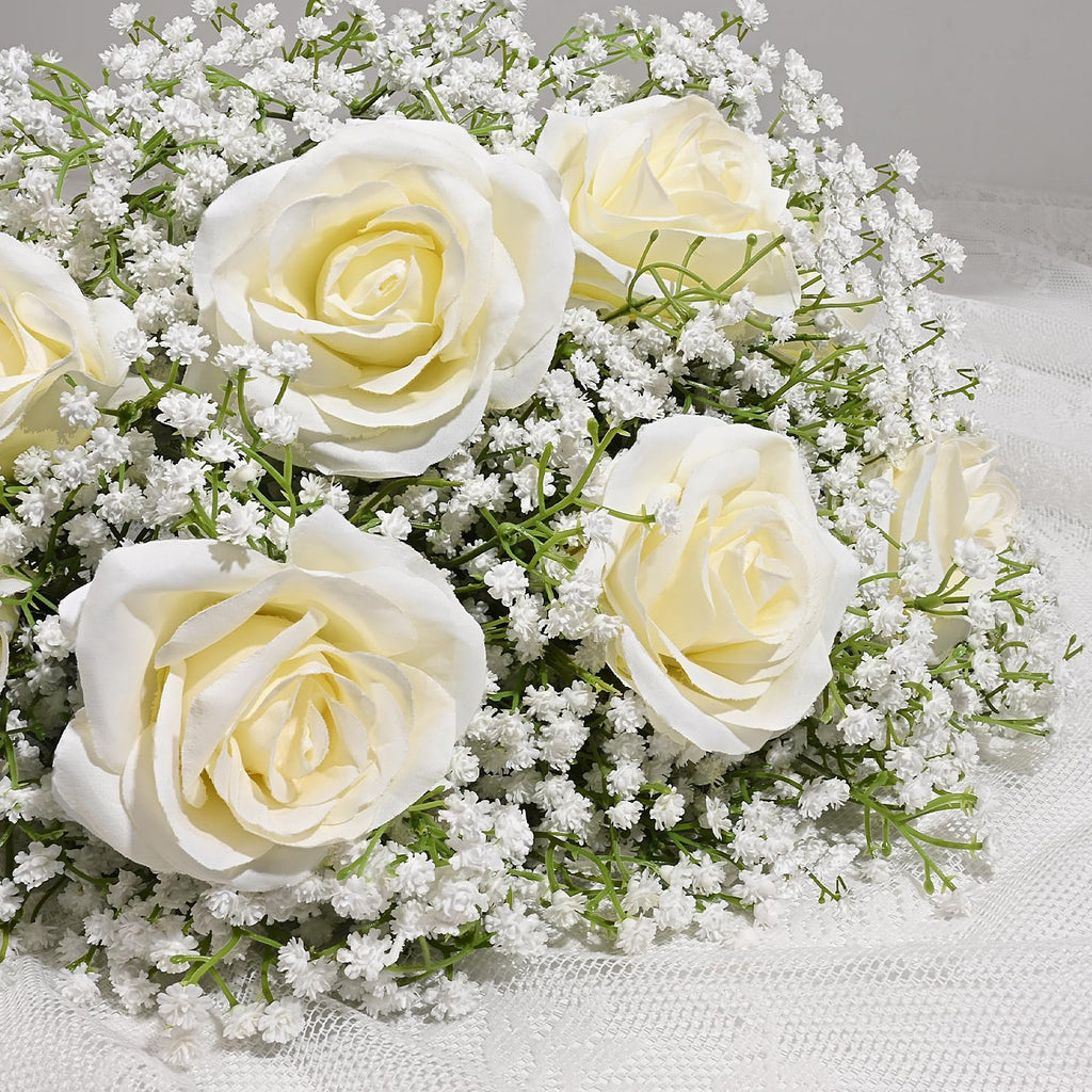 Close-up of a bouquet of white artificial roses and baby's breath flowers on a white lace fabric.