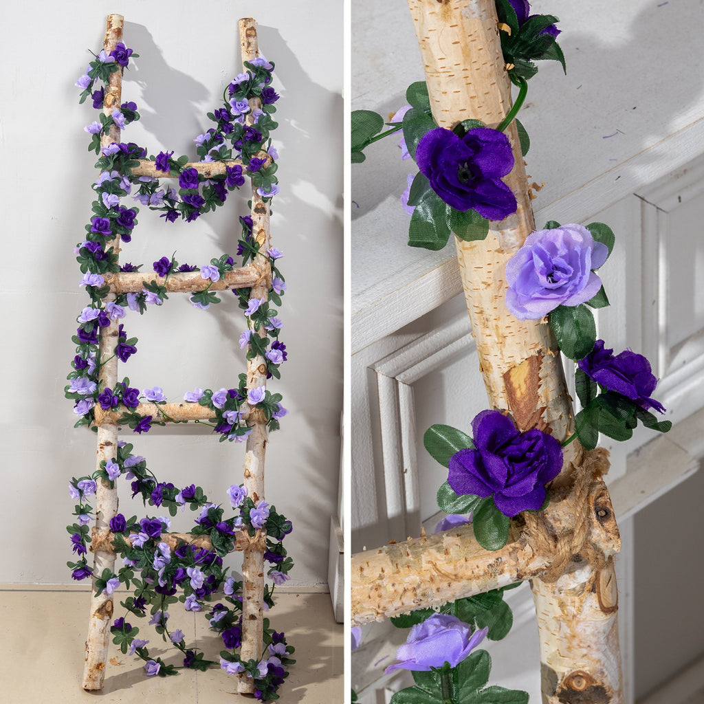 Artificial purple rose garland draped on a wooden ladder, showing close-up details of flowers and leaves.