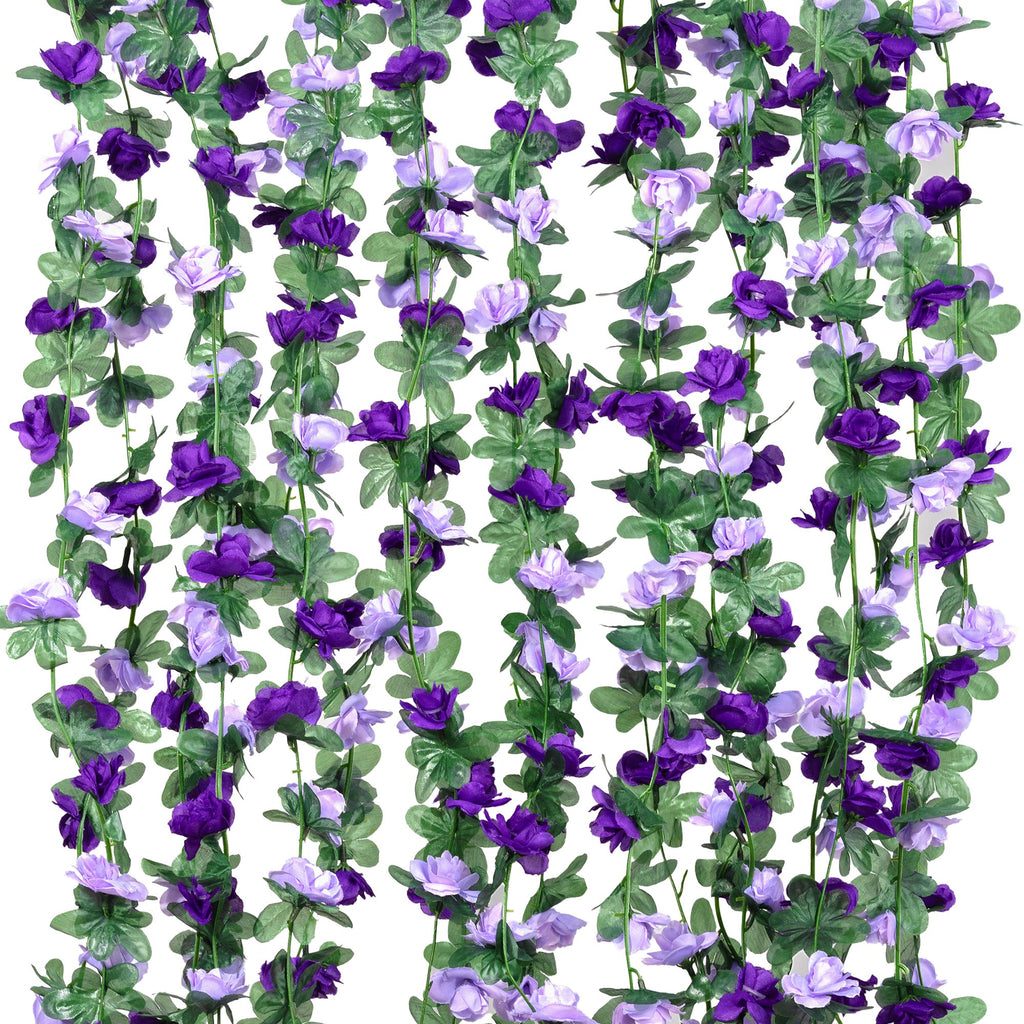 Artificial purple rose garlands with green leaves hanging vertically against a white background.
