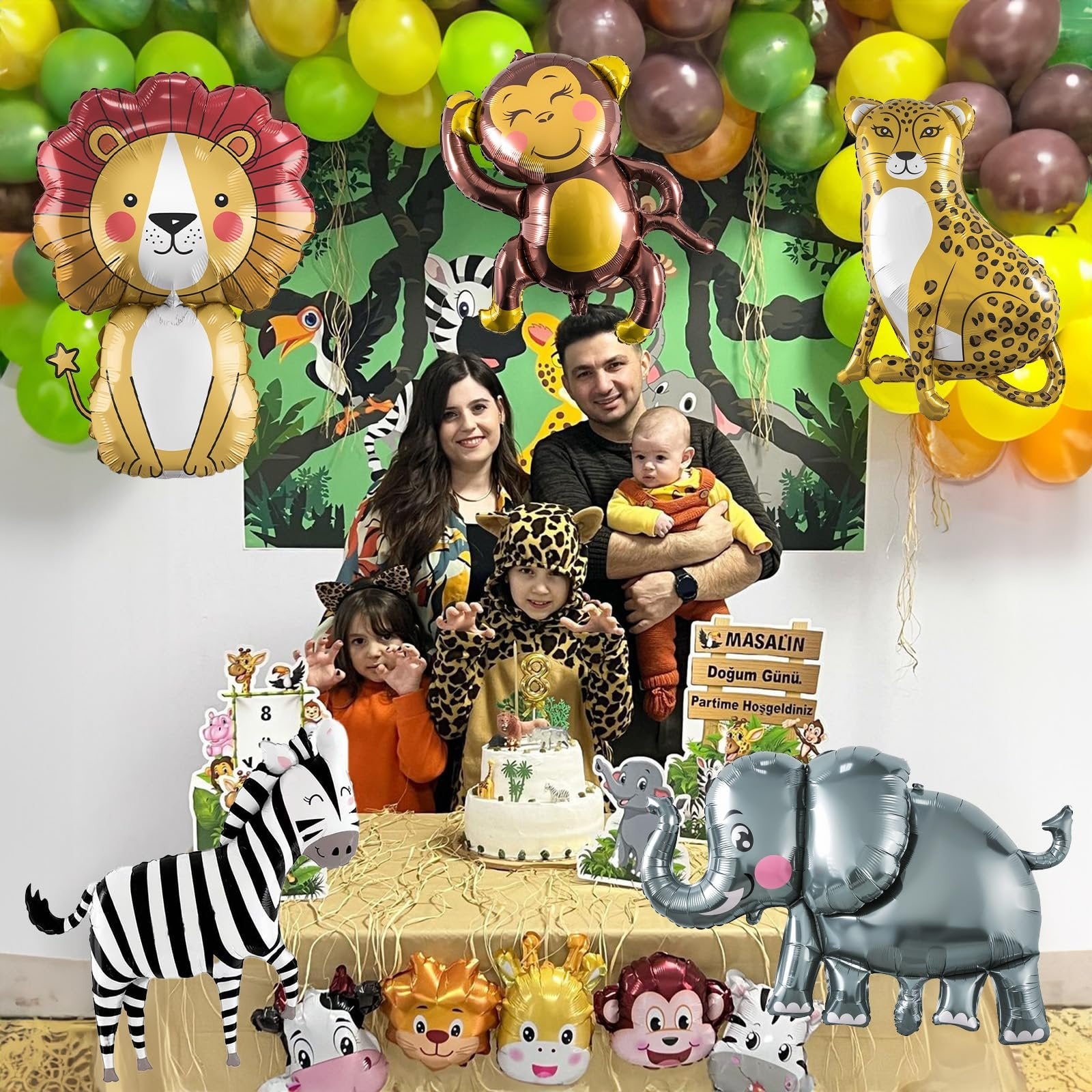 Family celebrating a safari-themed birthday with animal balloons and a cake
