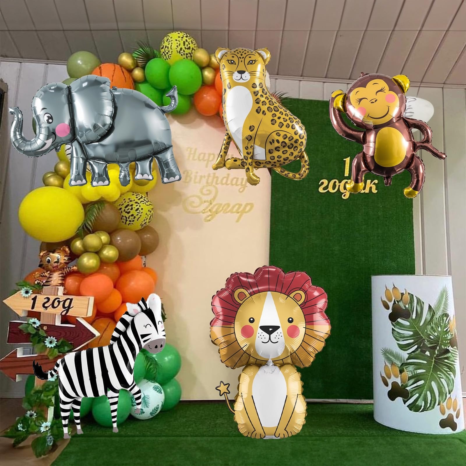 Safari animal balloons including elephant, leopard, monkey, lion, and zebra, arranged with a balloon arch and greenery for a party backdrop.