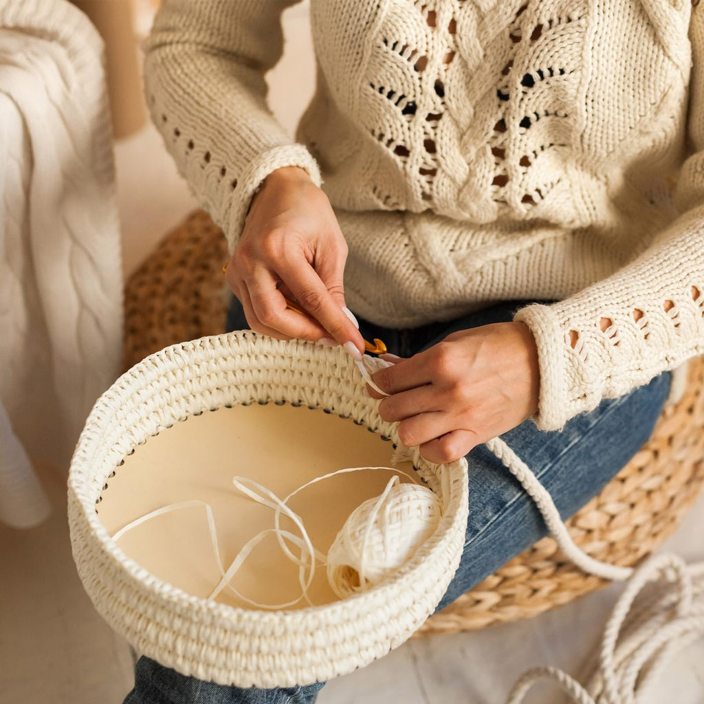 Person crocheting a basket base with yarn and a hook, showing the process of crafting.