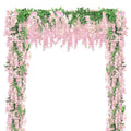 Pink wisteria flower garland with green leaves draped over an archway against a white background
