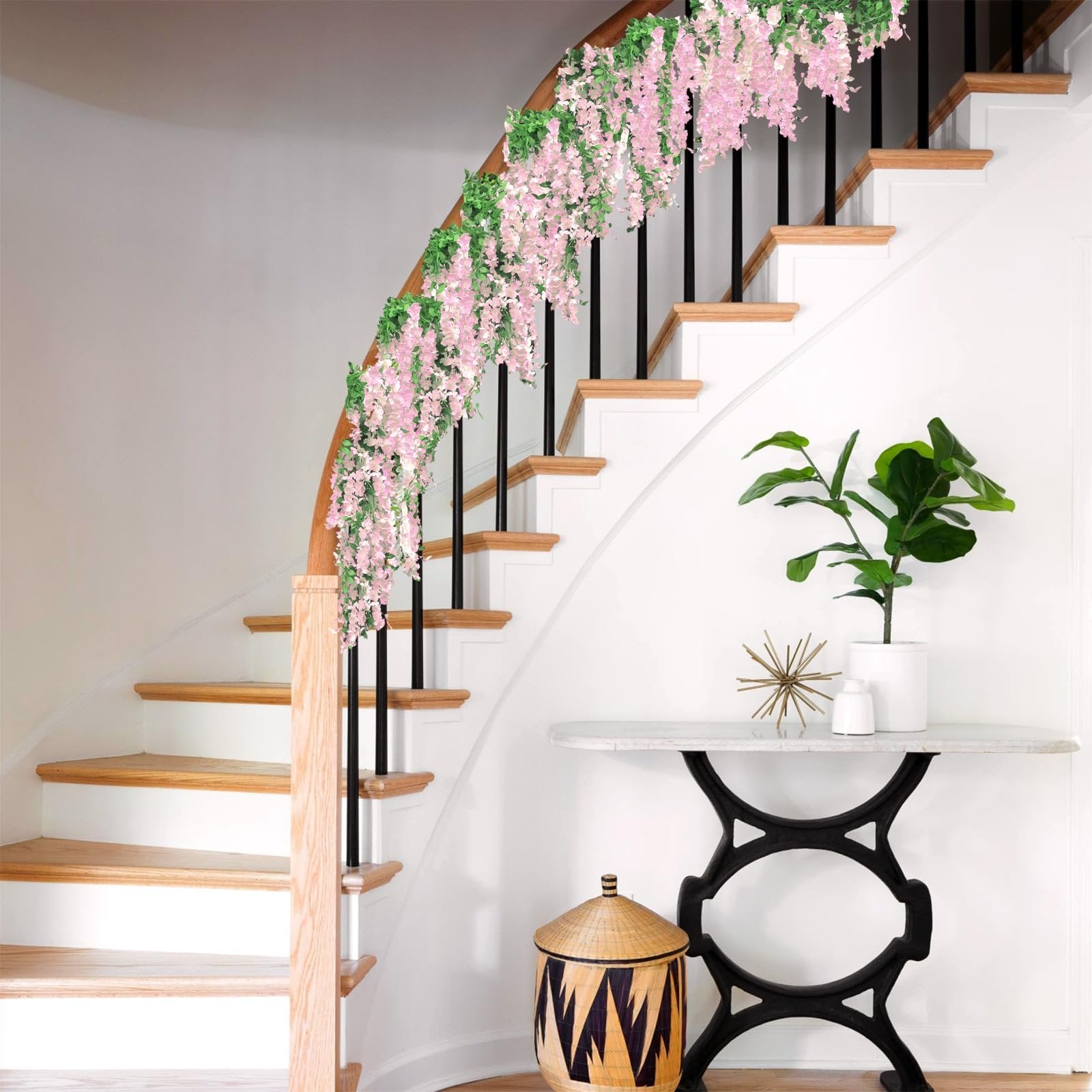 Pink wisteria garland draped over a staircase railing with green leaves