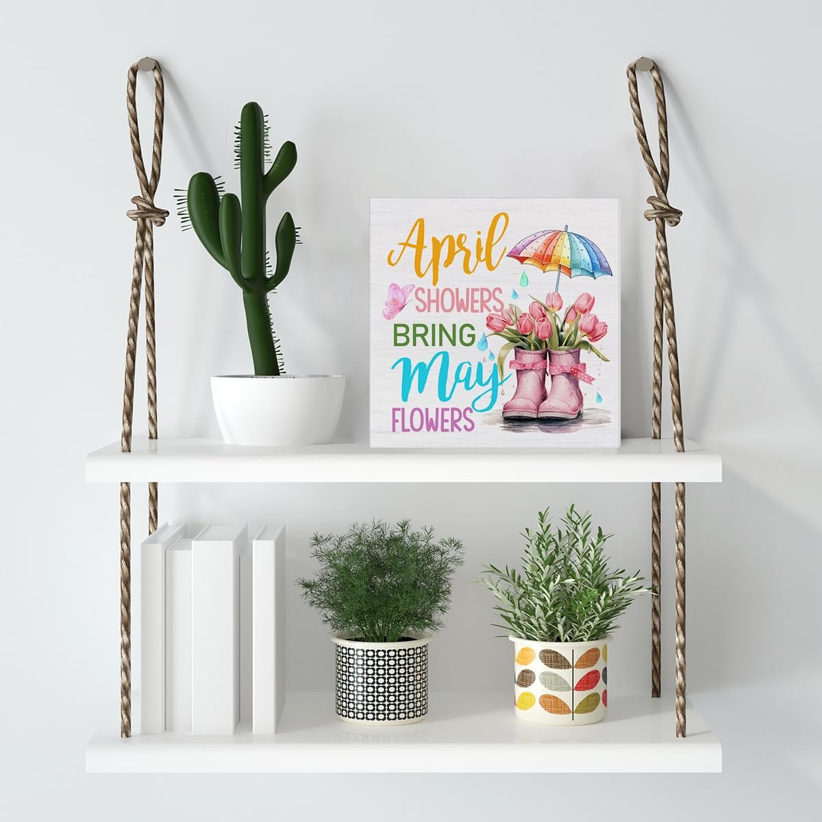 Wooden spring sign with text 'April Showers Bring May Flowers' and illustration of pink boots with tulips under a rainbow umbrella.