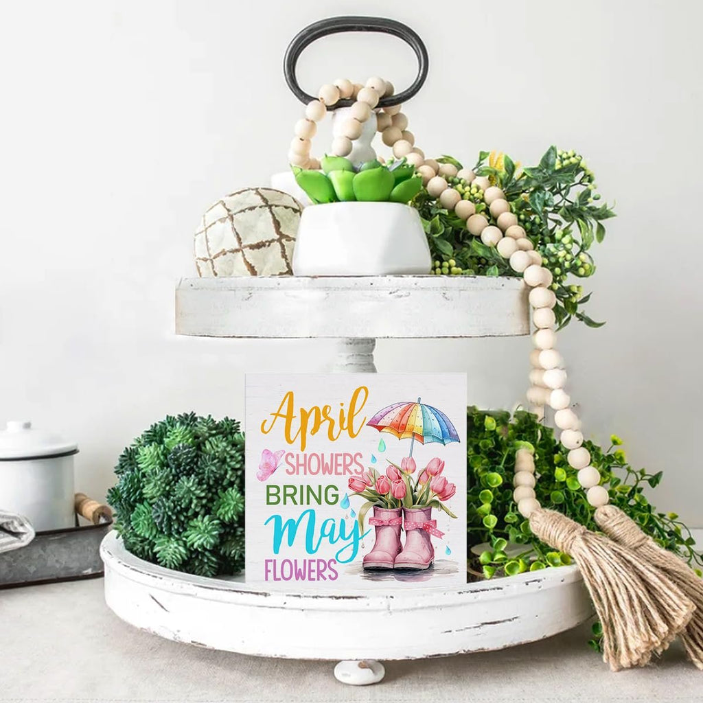 Wooden spring sign with 'April Showers Bring May Flowers' text and illustration of tulips in boots under an umbrella.