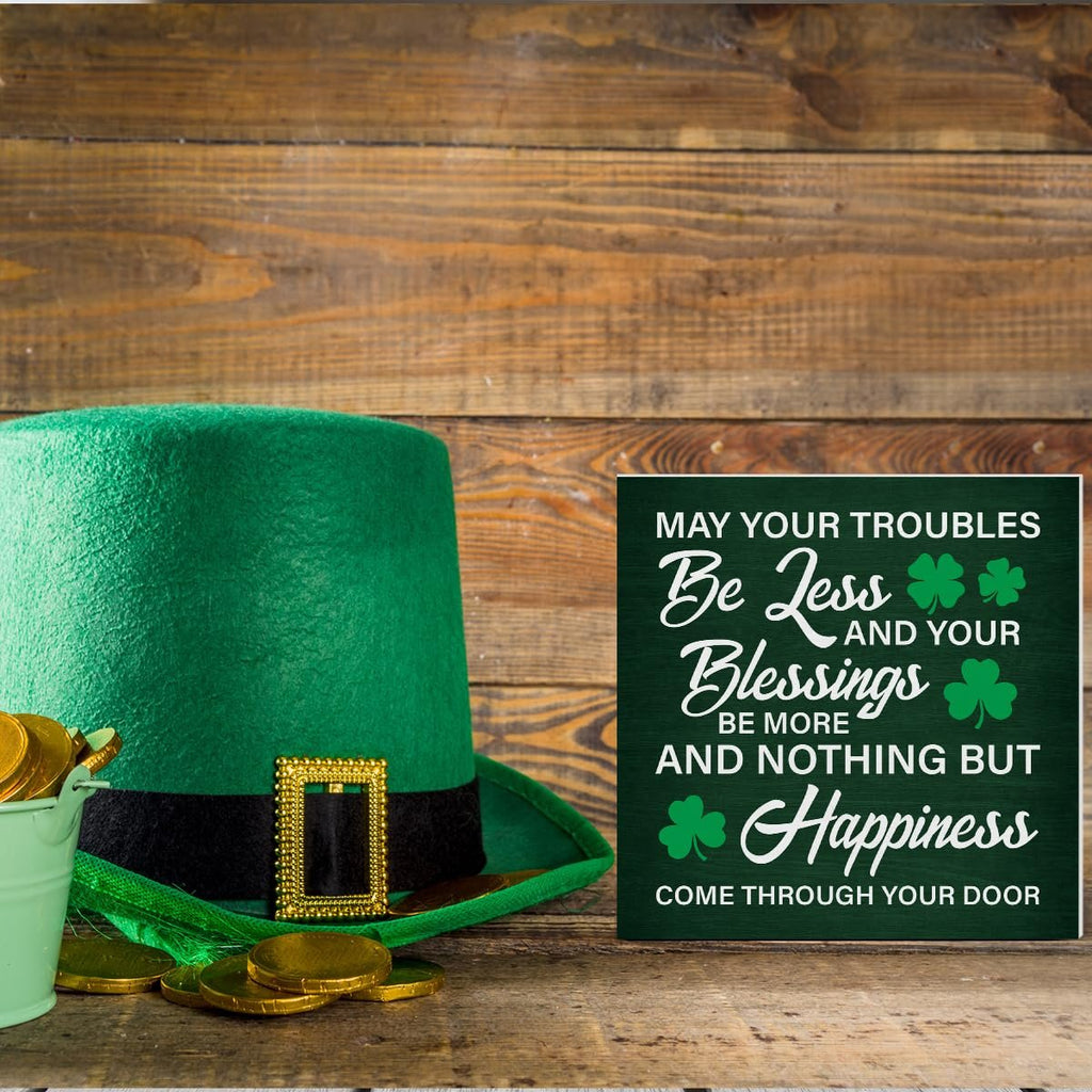 Green St. Patrick's Day sign with Irish blessing, next to a leprechaun hat and gold coins on a wooden surface.